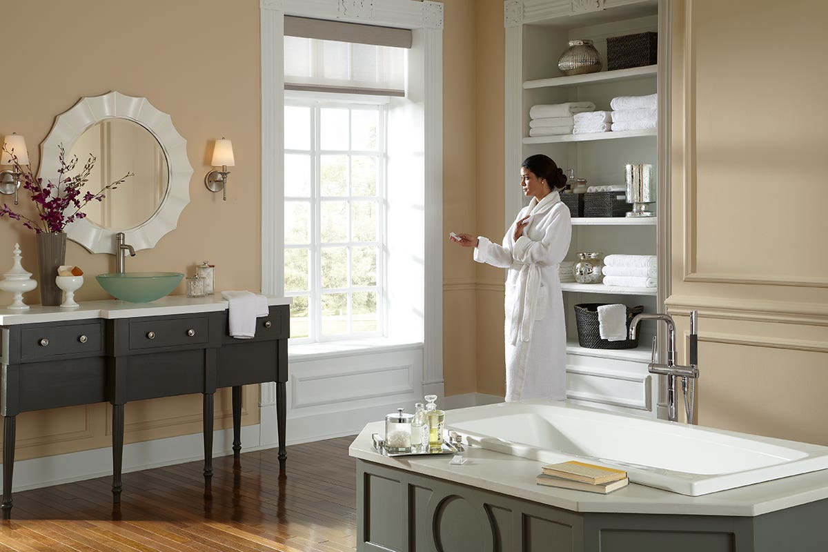 Woman in Bright Bathroom Closing Sheer Roller Shades with Remote Control