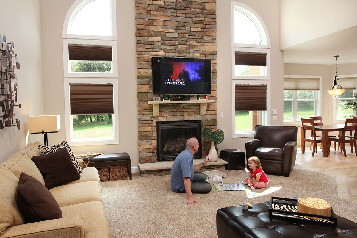 Man in Family Room Closing Room Darkening Honeycomb Shades with Remote Control